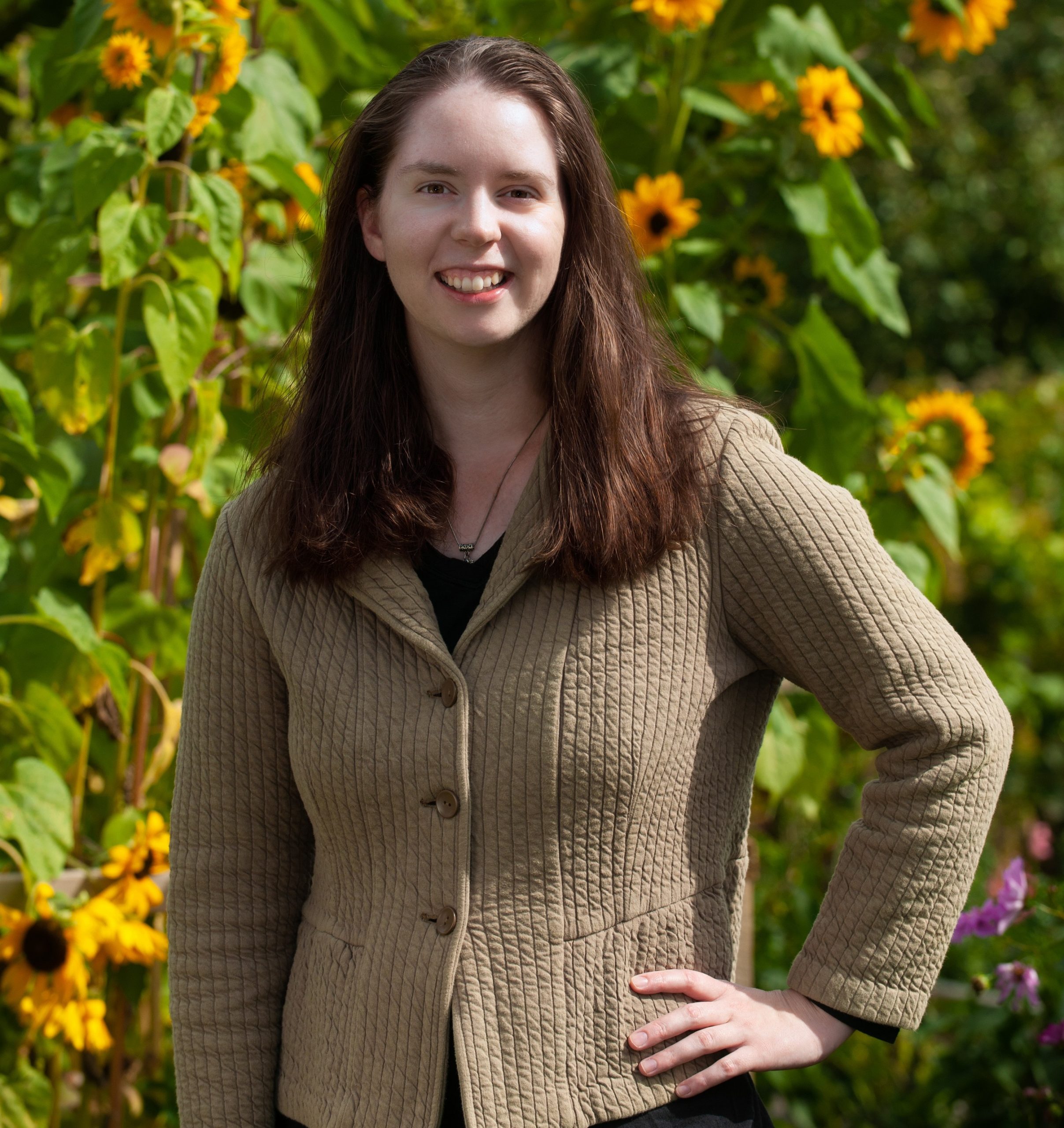 A photo of author Anna Rose Johnson in front of a patch of sunflowers.