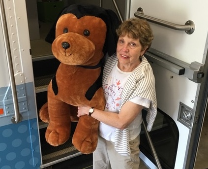 Photo of Pamela Cameron with a large stuffed animal of Sport the Ship Dog.