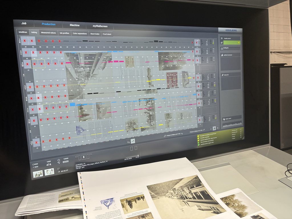 A laptop screen with an image and text layout from "A City On Three Lakes." The layout is overlaid with a numbered grid that includes various symbols in each slot, such as red Xs, and barcode-like patterns of blue, pink, yellow, or black lines.